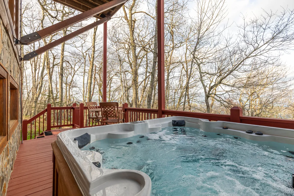 A tranquil outdoor hot tub sits on a wooden deck surrounded by trees. The setting is peaceful, ideal for relaxing and soaking after a day outdoors.