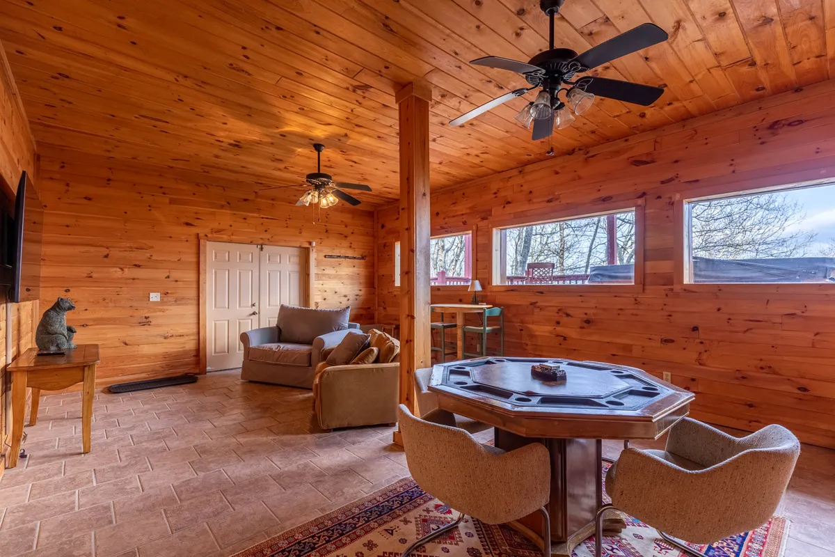 A welcoming interior scene featuring a round dining/game table, comfortable seating area, and warm wooden accents. The space is clearly suited for social gatherings, meals, and games, exuding a playful and relaxed vibe.